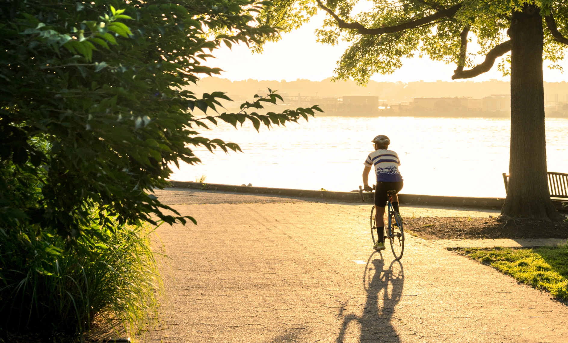 Outdoor cyclist enjoying peaceful riverside ride with scenic sunset and waterfront backdrop